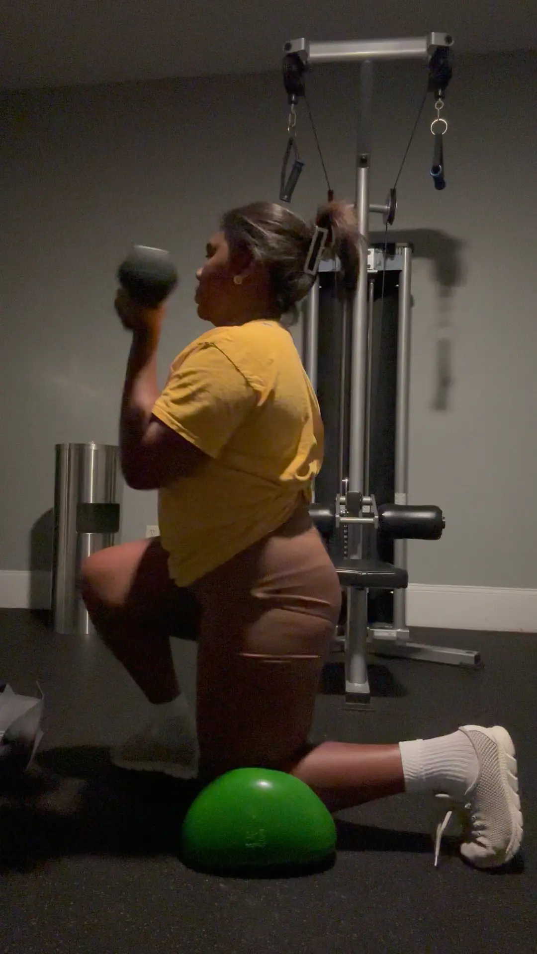 Person holding a dumbbell and kneel on a green Air8 in a gym