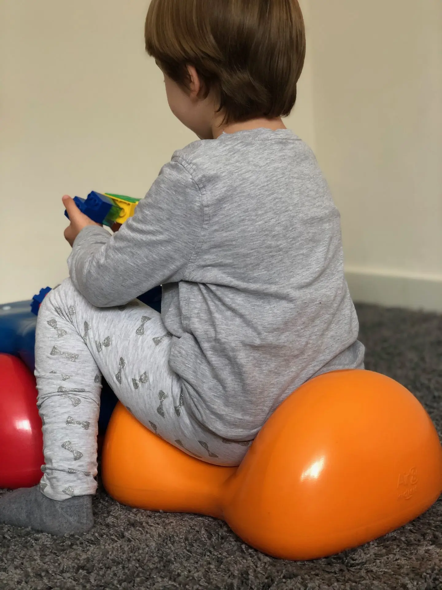 Child playing with toys on an orange Air8 kidisit