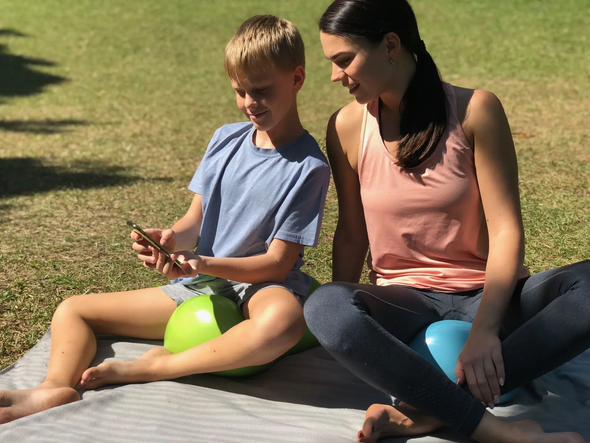 Son showing his mom a video on his phone in the park while sitting on the Air8 Cushion